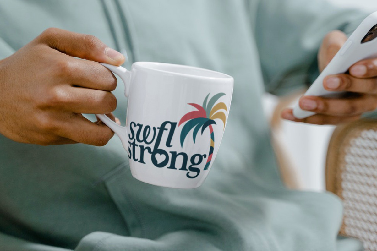 Person holding a mug with logo on it